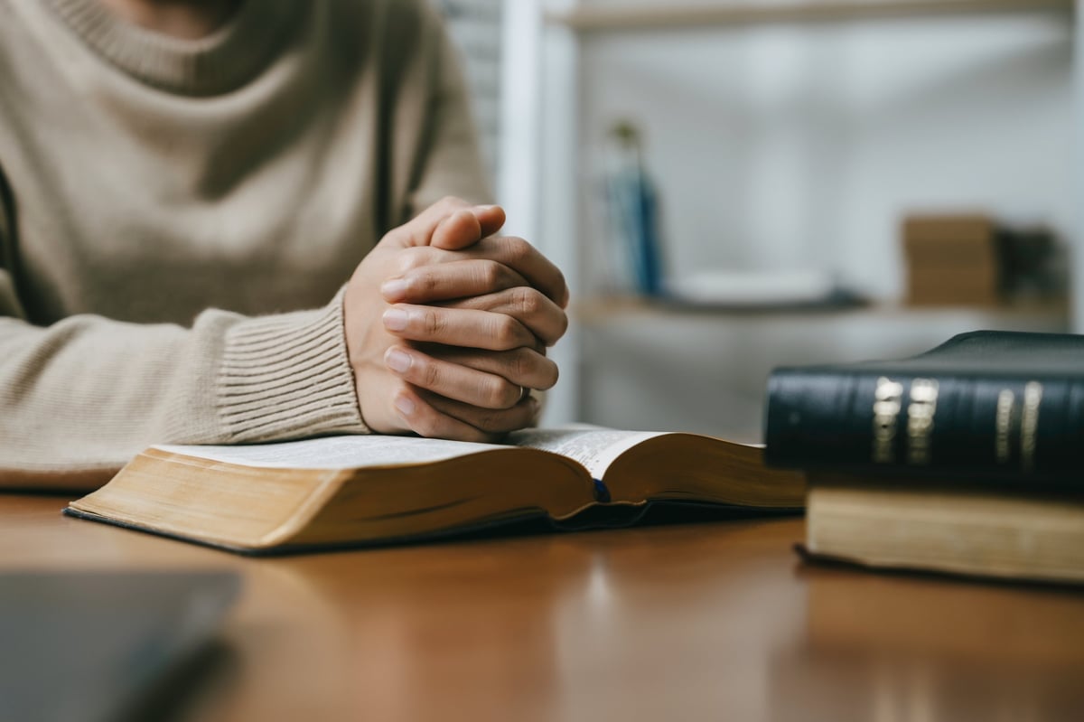 A person praying over an open Bible
